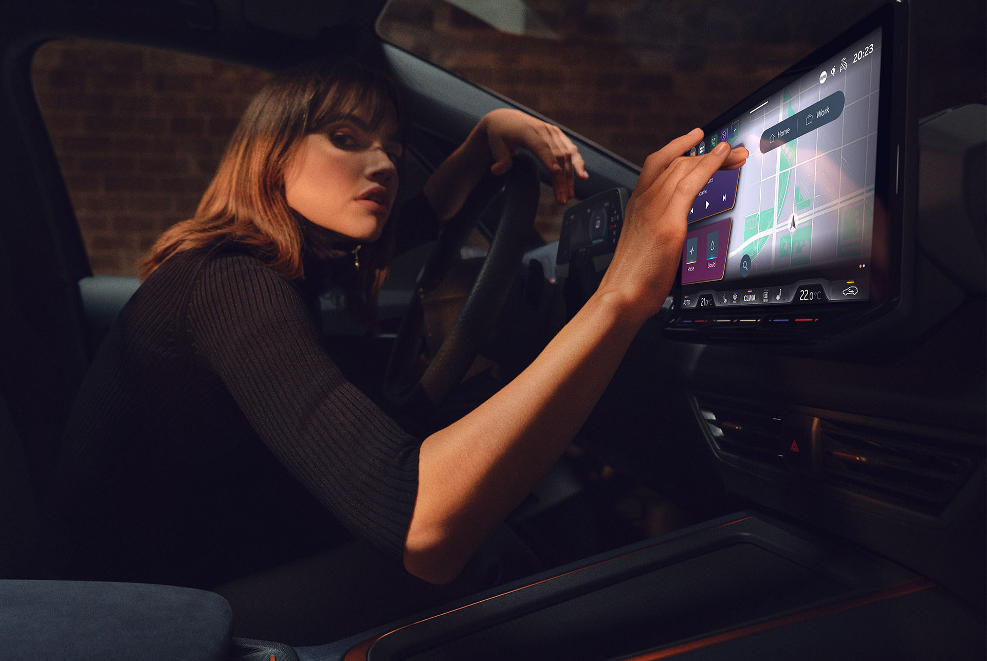Femme à l’intérieur d’une CUPRA Born 2024 utilisant le tableau de bord et l’écran d’infotainment