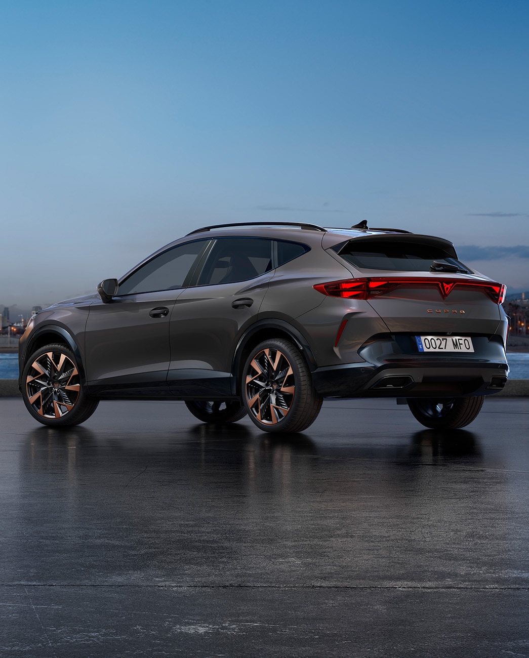 Le nouveau CUV CUPRA Formentor 2024 en Gris Graphène garé sur la promenade du front de mer au crépuscule. L’arrière-plan est un paysage urbain avec des gratte-ciel et des palmiers illuminés par la lumière déclinante du jour.