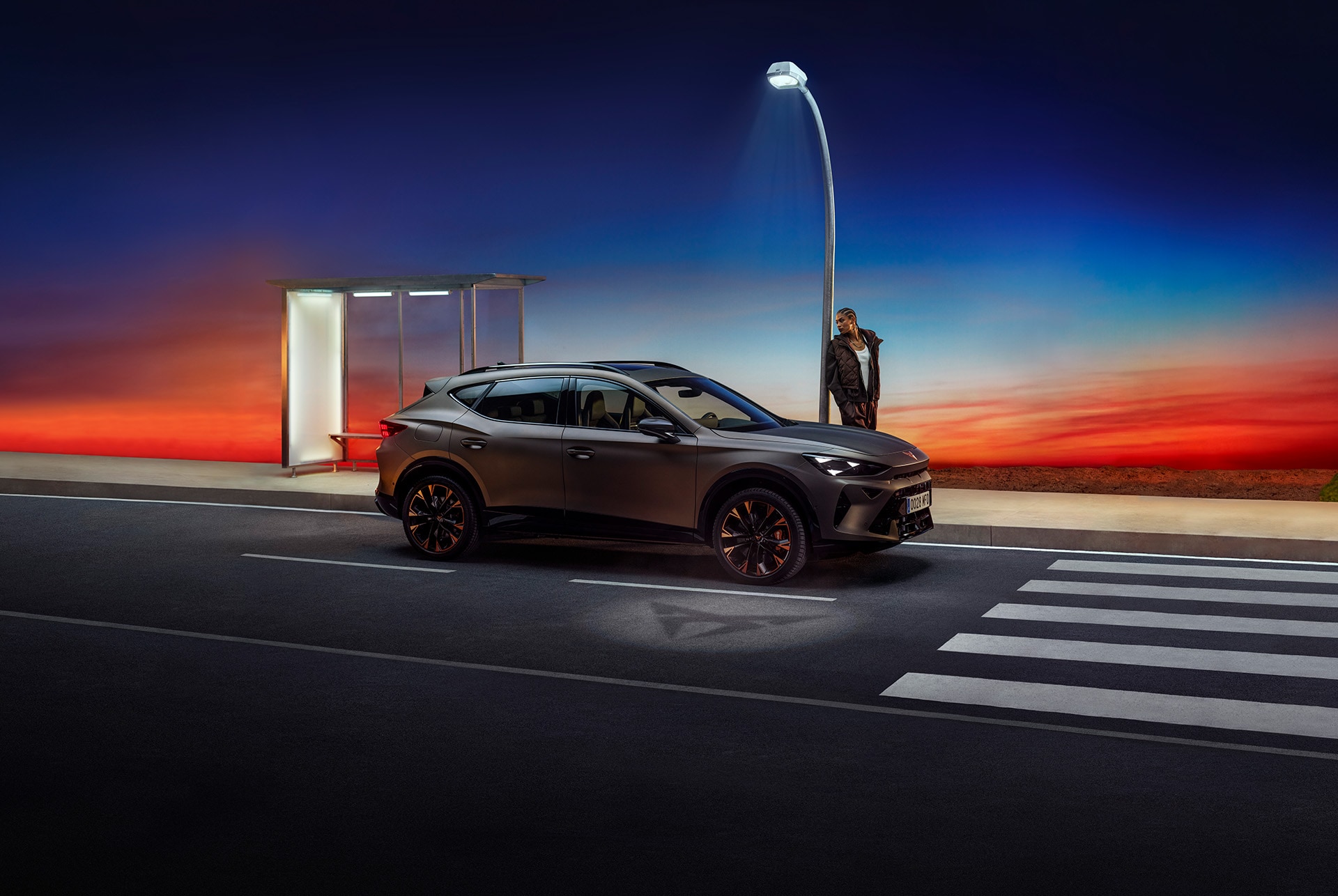 Vue latérale de la carrosserie du nouveau CUPRA Formentor VZ 2025 en Bronze Century mat, modèle avec des jantes cuivrés. Architecture illuminée et béton.