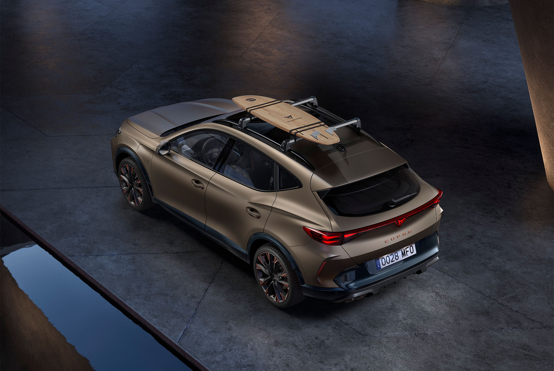 Vue du dessus de la nouvelle CUPRA Formentor 2024 en Century Bronze mat avec porte-surfs sur le toit de la voiture, voiture garée sur le béton.