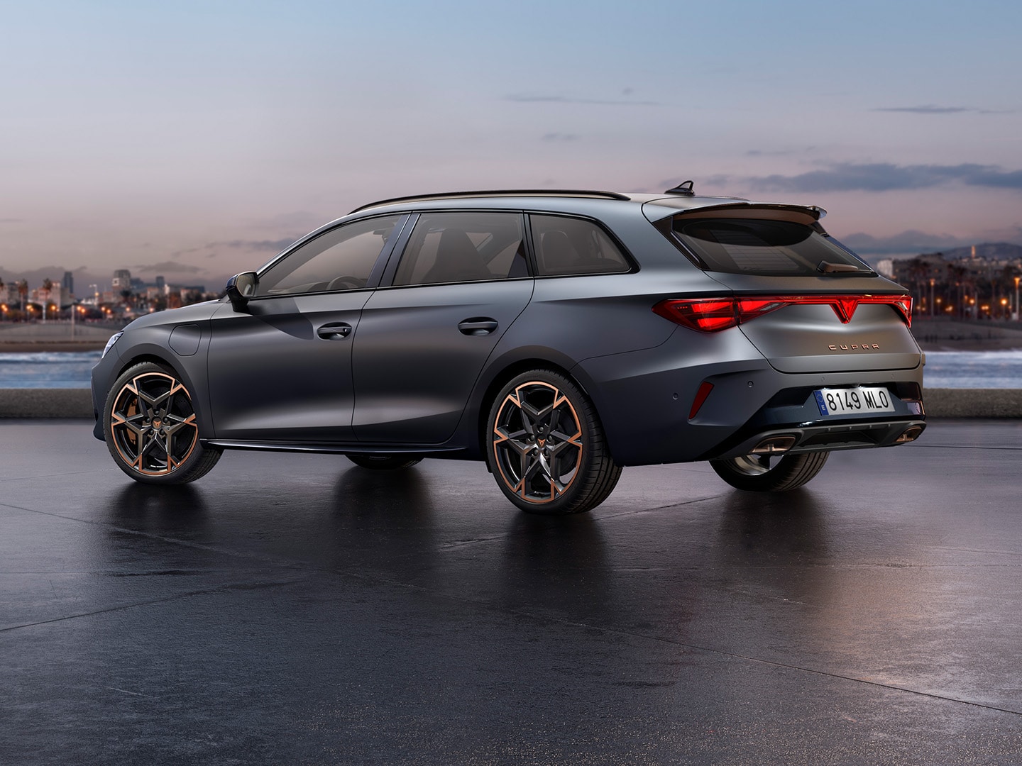 Vue arrière de la CUPRA Leon Sportstourer garée dans un environnement bétonné avec la mer et la skyline en arrière-plan.