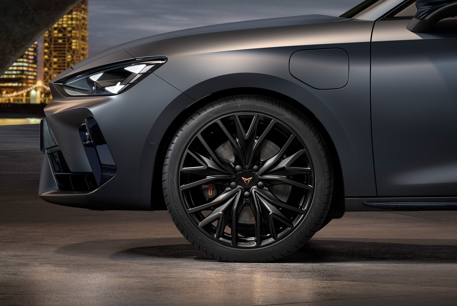 Vue avant latérale de la jante gauche en Noir Sport Mat de la nouvelle CUPRA Leon Sportstourer 2025, avec les pneus, les phares signature et la carrosserie grise.