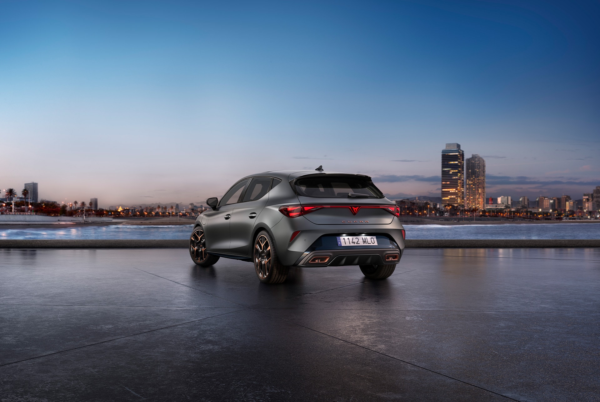Vue arrière de la nouvelle CUPRA Leon 2025 en gris, stationnée dans un cadre urbain lumineux au coucher du soleil
