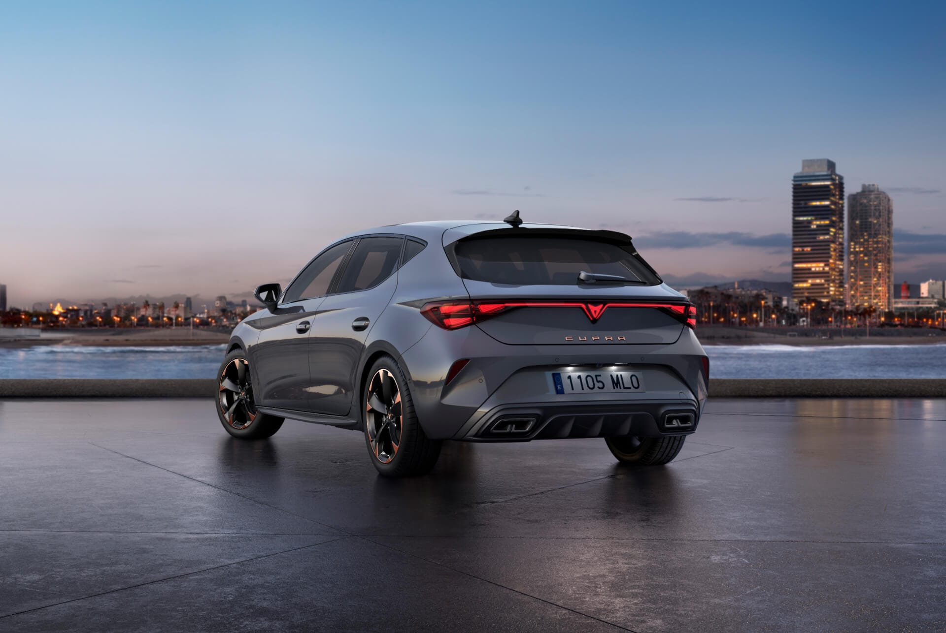 Vue arrière du nouveau modèle Cupra Leon 2024 en Gris Brillant avec réglage adaptatif du châssis et jantes en alliage noir et cuivre. Ville en arrière-plan au coucher du soleil.