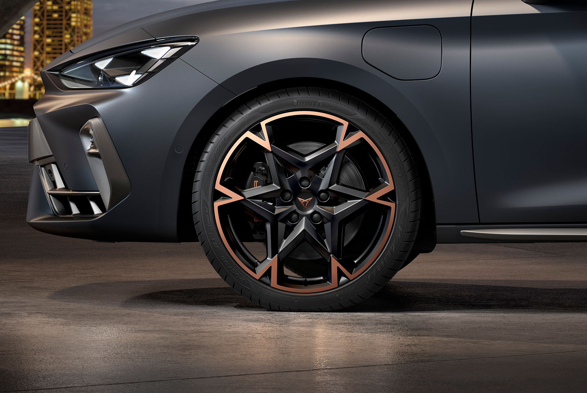 Vue latérale avant gauche des jantes en alliage usinées en Noir et Cuivre, pneus, phares signature et carrosserie en gris mat de la nouvelle Cupra Leon 2024