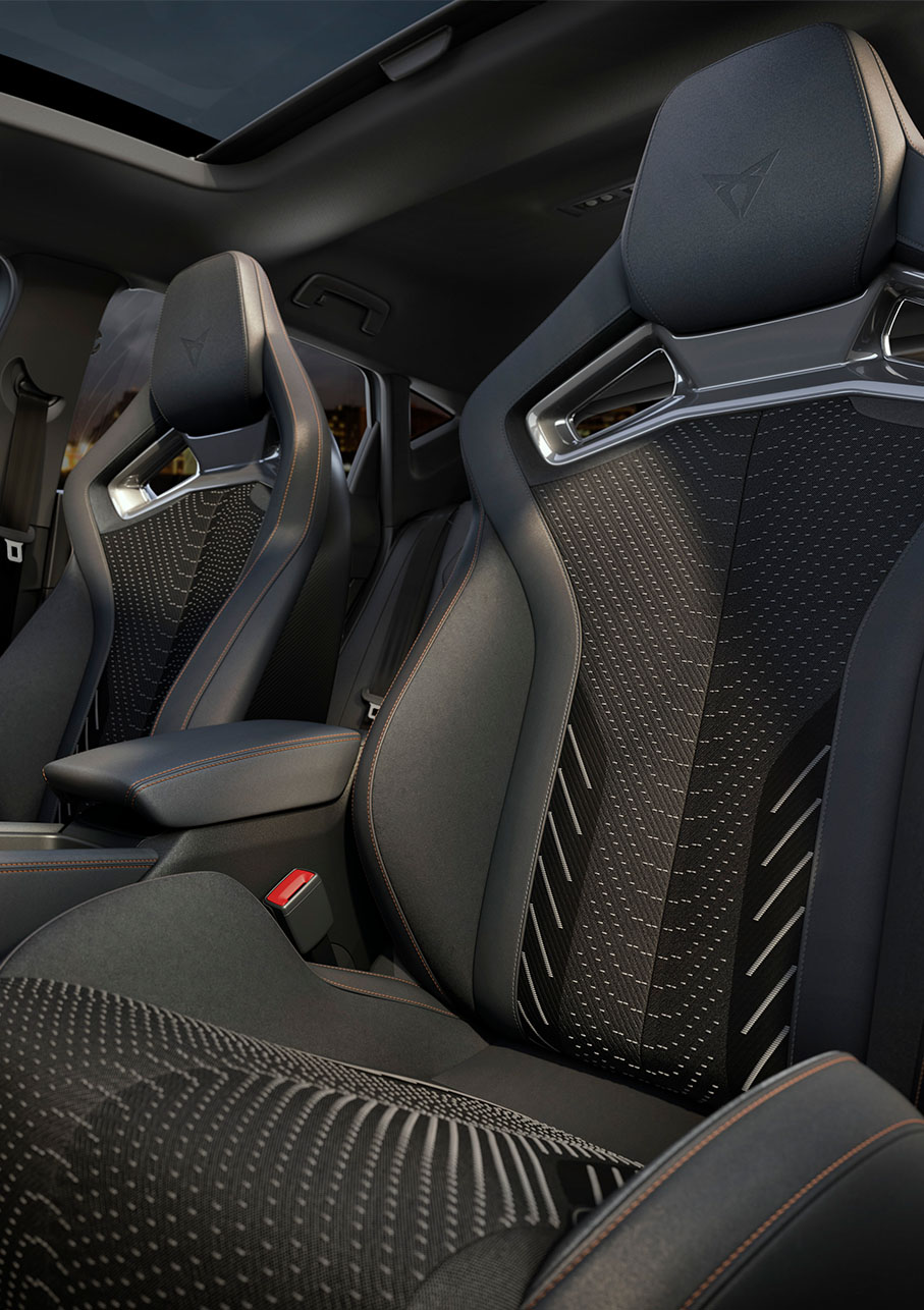Espace conducteur de la nouvelle Cupra Leon 2024 hybride, sièges-baquets CUP, phares Matrix LED Cupra, freins performants et jantes forgées en option, volant et paysage urbain. 