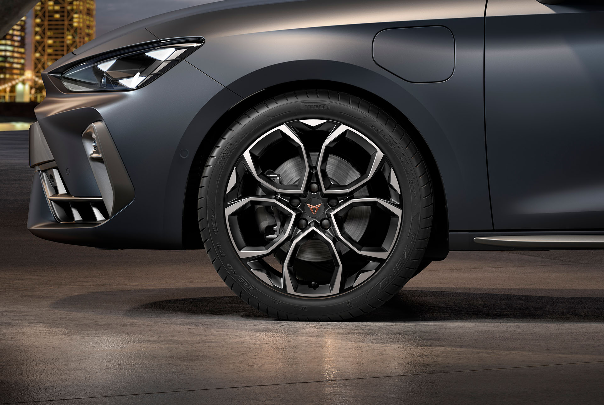 Vue latérale avant gauche des jantes en alliage usinées en Argent et Noir Tempête, pneus, phares signature et carrosserie grise de la nouvelle Cupra Leon 2024