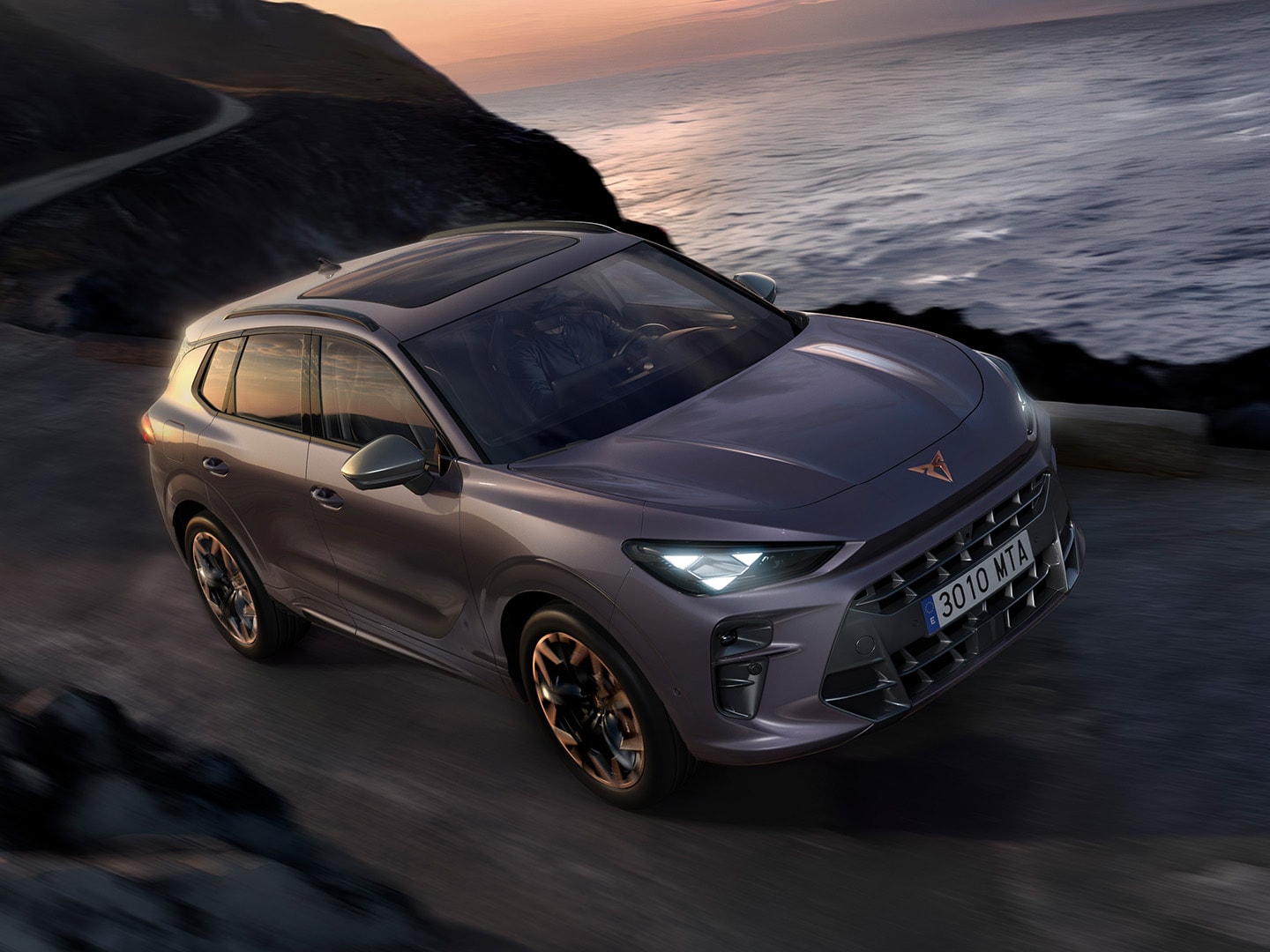 CUPRA Terramar roulant sur une route en bord de mer, avec réglage adaptatif du châssis (DCC), coloris Violet intersidéral et jantes en alliage 20" Cuivrées Hadron. 
