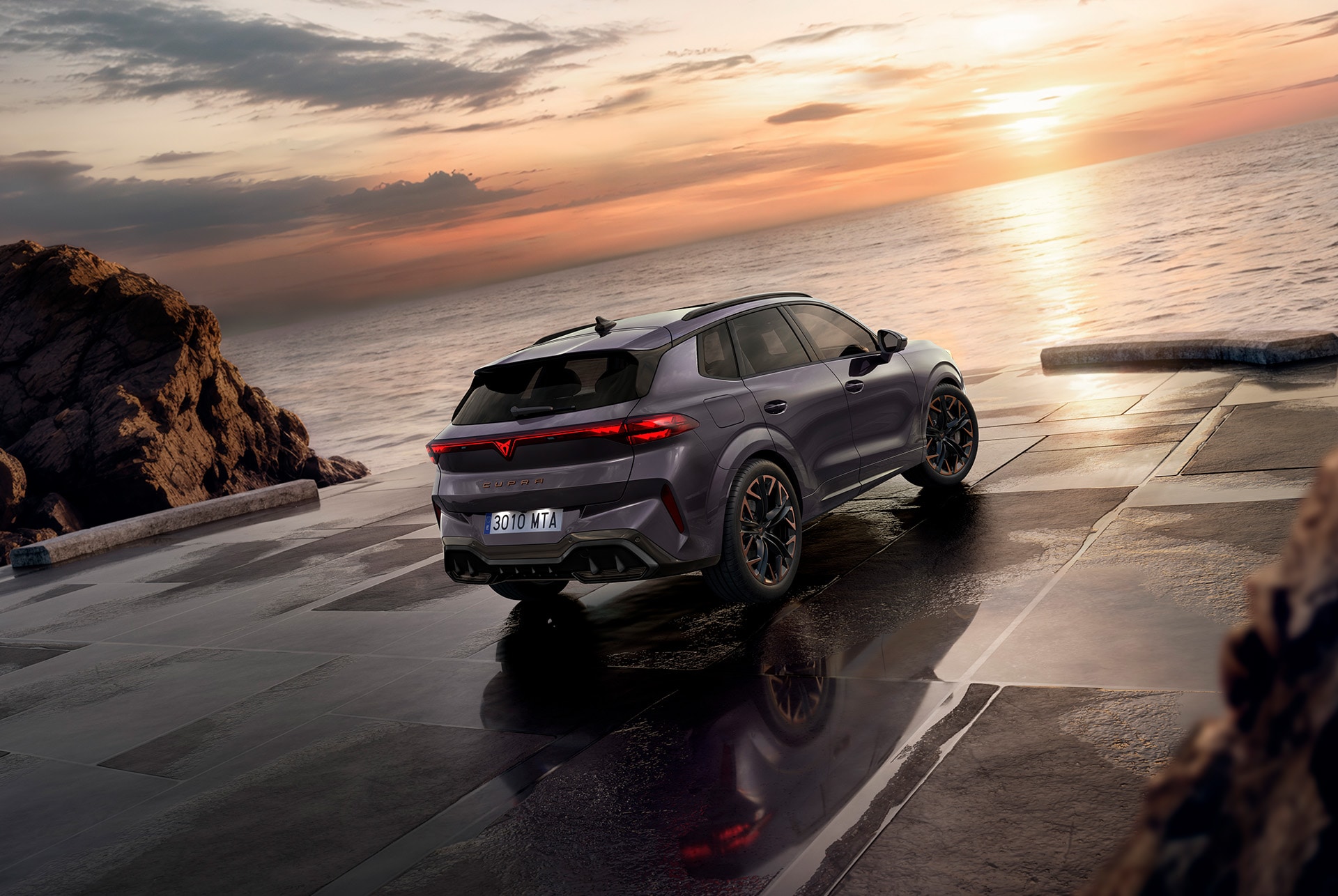 suv hybride CUPRA Terramar, nouveau modèle 2025, vue arrière, avec des feux arrière élégants sublimés par le logo cupra, des jantes en alliage modernes et une carrosserie sportive sur une chaussée mouillée en bord de mer.