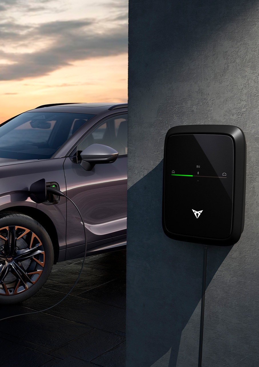 nouveau véhicule hybride rechargeable CUPRA Terramar en charge, devant le coucher du soleil en bord de mer.