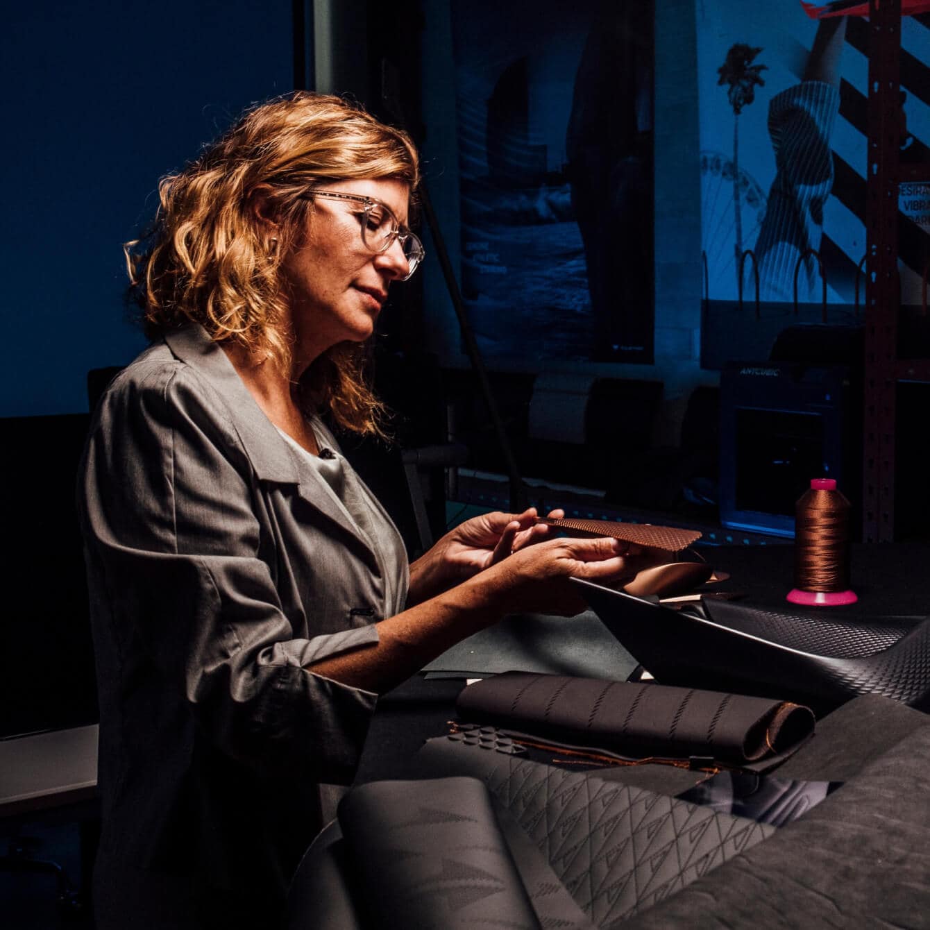 Francesca Sangallo, la Directrice Créative, travaillant sur un tissu dans un atelier sombre.