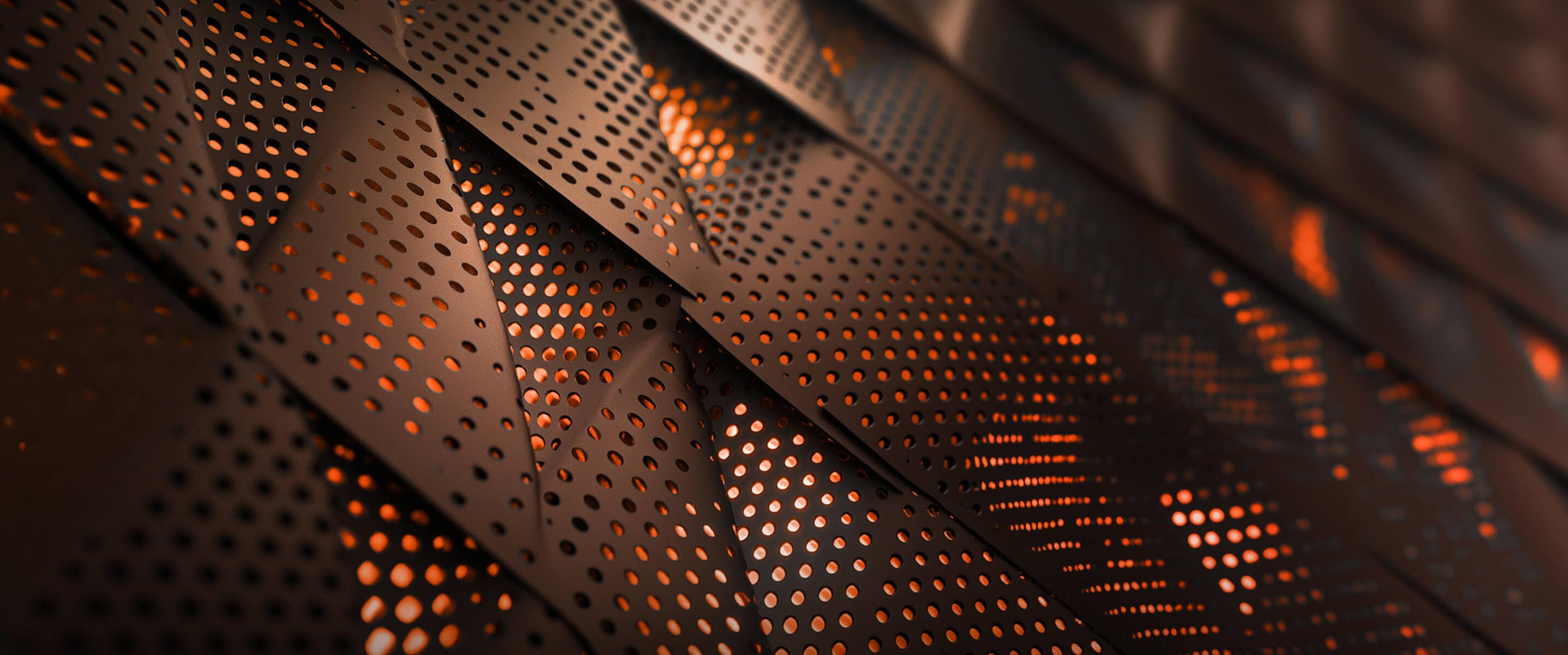 Gros plan de panneaux métalliques perforés avec une lumière orange qui brille à travers les trous. 
