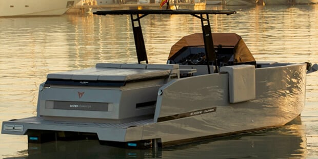 Bateau à moteur gris dans une marina, paysage urbain en arrière-plan.