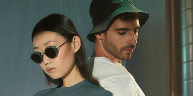 : Deux modèles, l’un aux cheveux foncés portant des lunettes de soleil et un t-shirt bleu, l’autre avec un bob vert et un t-shirt blanc, arrière-plan flou.