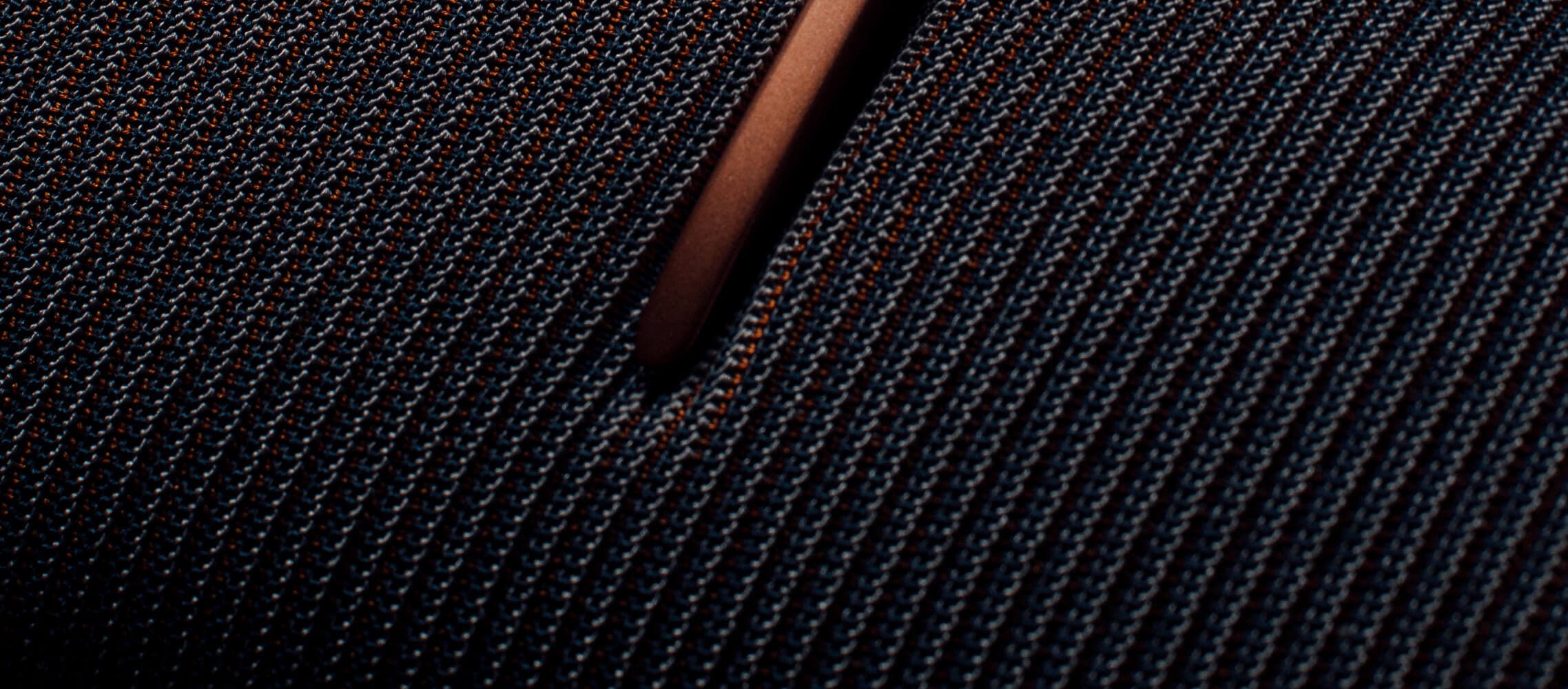 Gros plan sur un tissu texturé, à mailles serrées, avec un motif bleu foncé et orange.
