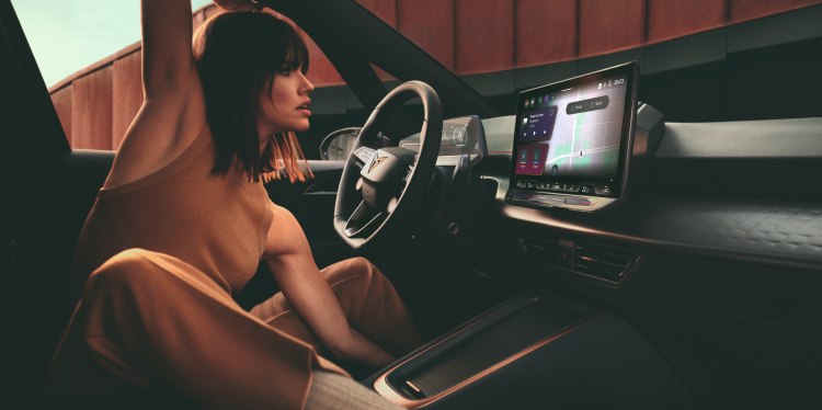 Une femme confortablement assise dans l'habitacle d'une voiture cupra, interagissant avec le système d'infodivertissement, mettant en valeur le design moderne.