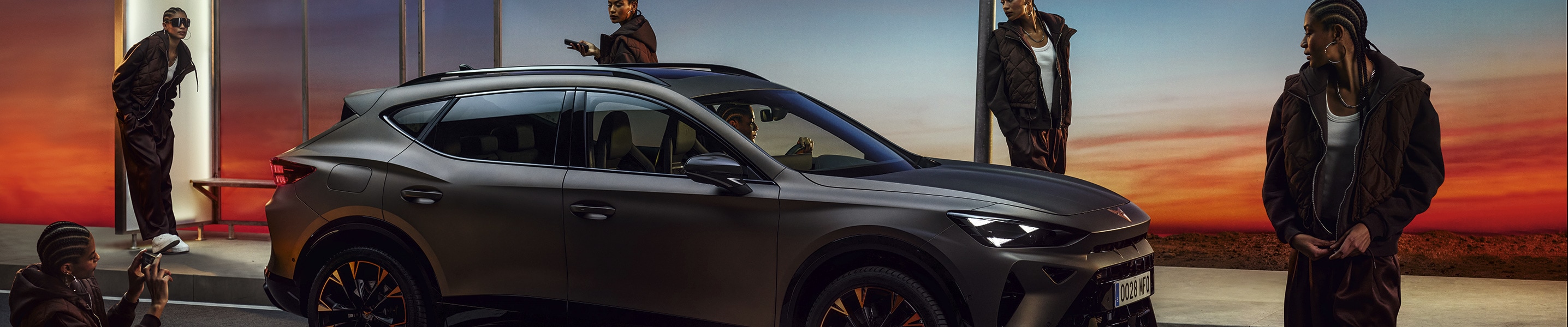 CUPRA Formentor en bronze century mat garée près d’un arrêt de bus au crépuscule, entourée de personnes, soulignant son design moderne et son attrait pour  la location de voitures de société et les gestionnaires de flotte.