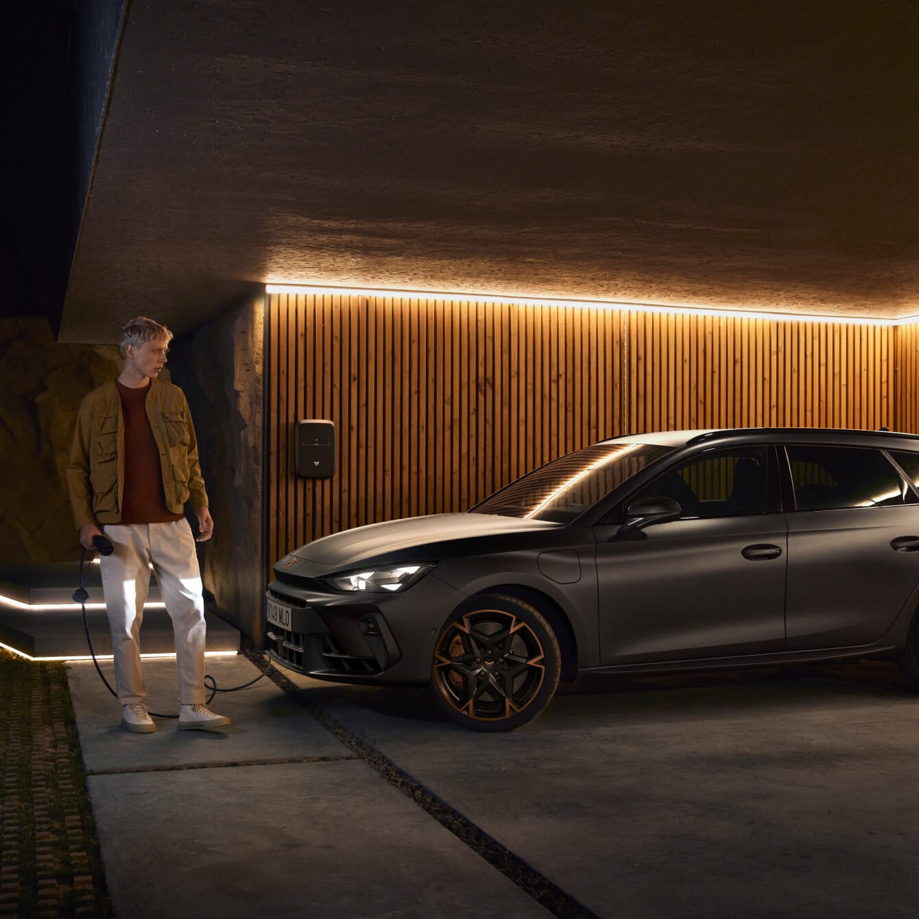 Hybride rechargeable pour la location de voitures d’entreprise, CUPRA Leon Sportstourer en gris mat technique, dans un garage éclairé avec des panneaux en bois.