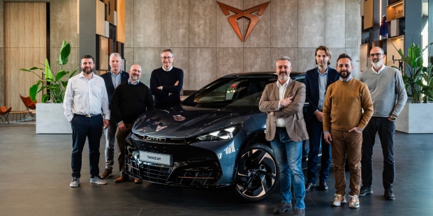 Véhicule cupra tavascan dans un showroom, avec des gestionnaires de flotte, logo cupra cuivré sur le mur.