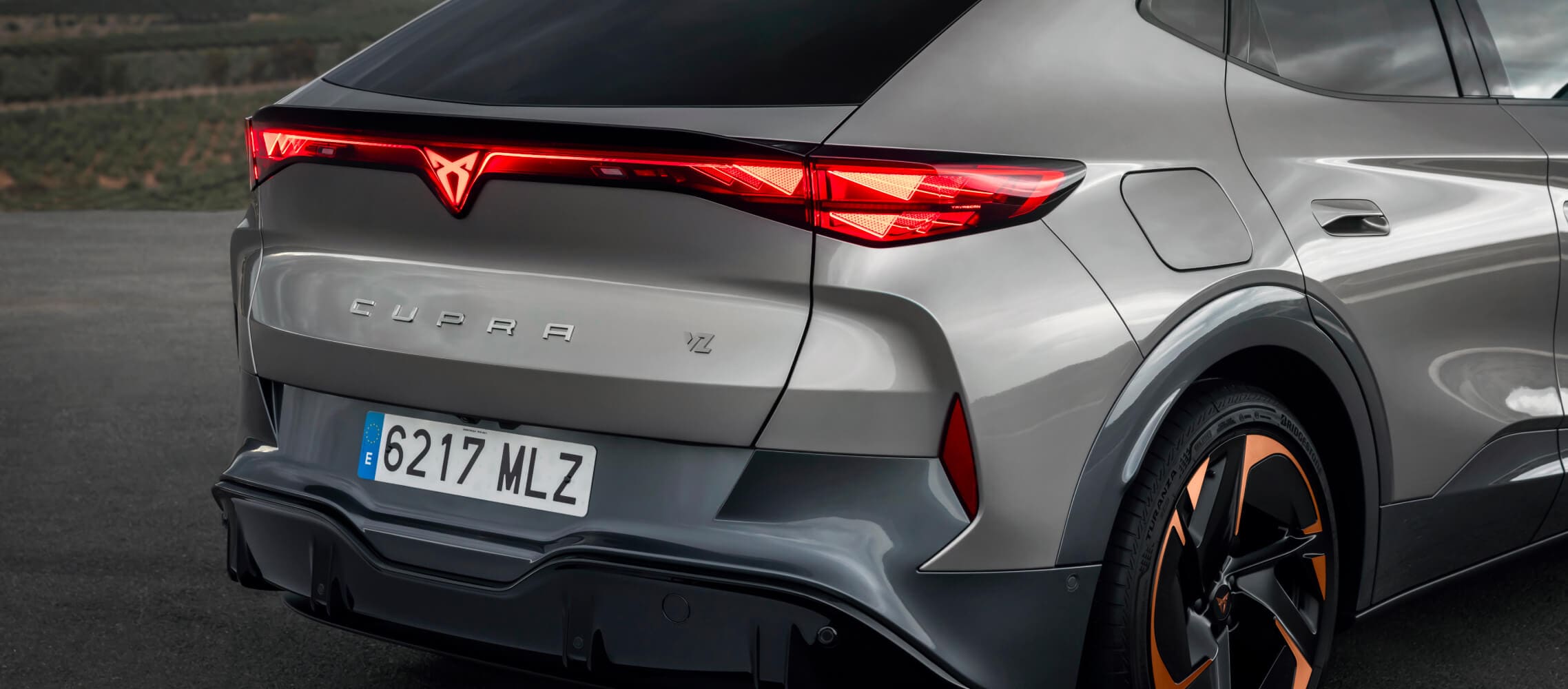 Voiture de société, cupra tavascan en gris, vue arrière, jantes aux accents cuivrés et éclairage à bandeau LED. 