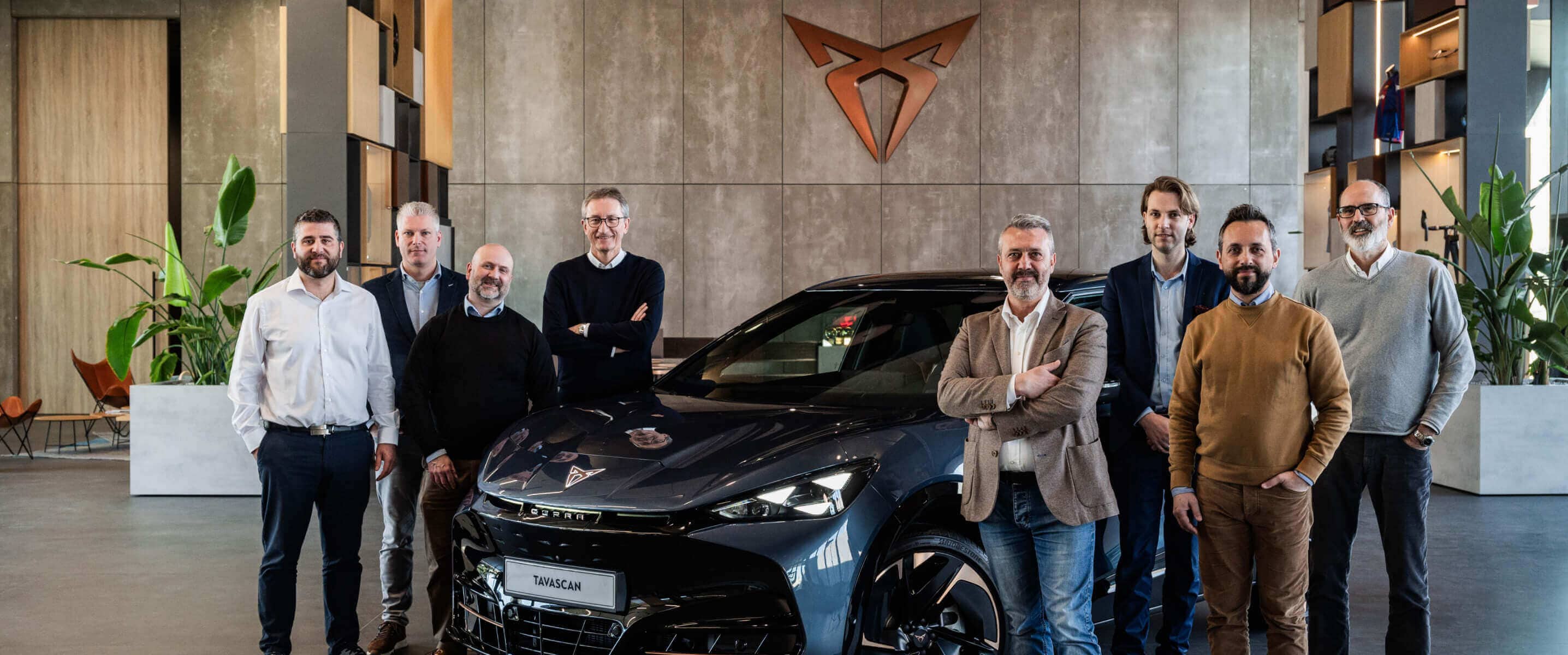 Véhicule cupra tavascan dans un showroom, avec des gestionnaires de flotte, logo cupra cuivré sur le mur.