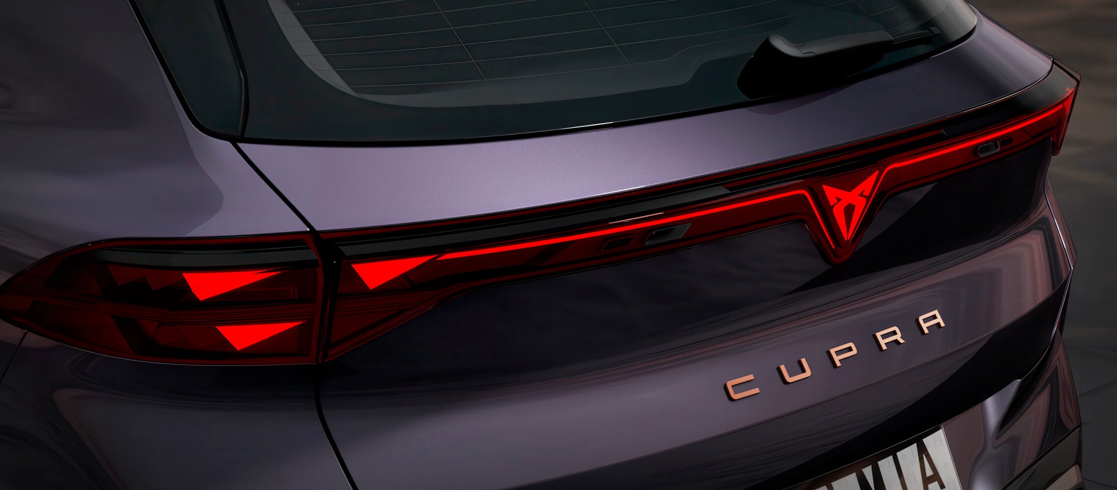 Gros plan sur l’arrière de la cupra terramar vz dans la couleur dark void, les feux arrière d’une hybride rechargeable, le logo cupra illuminé et le lettrage aux accents cuivrés.