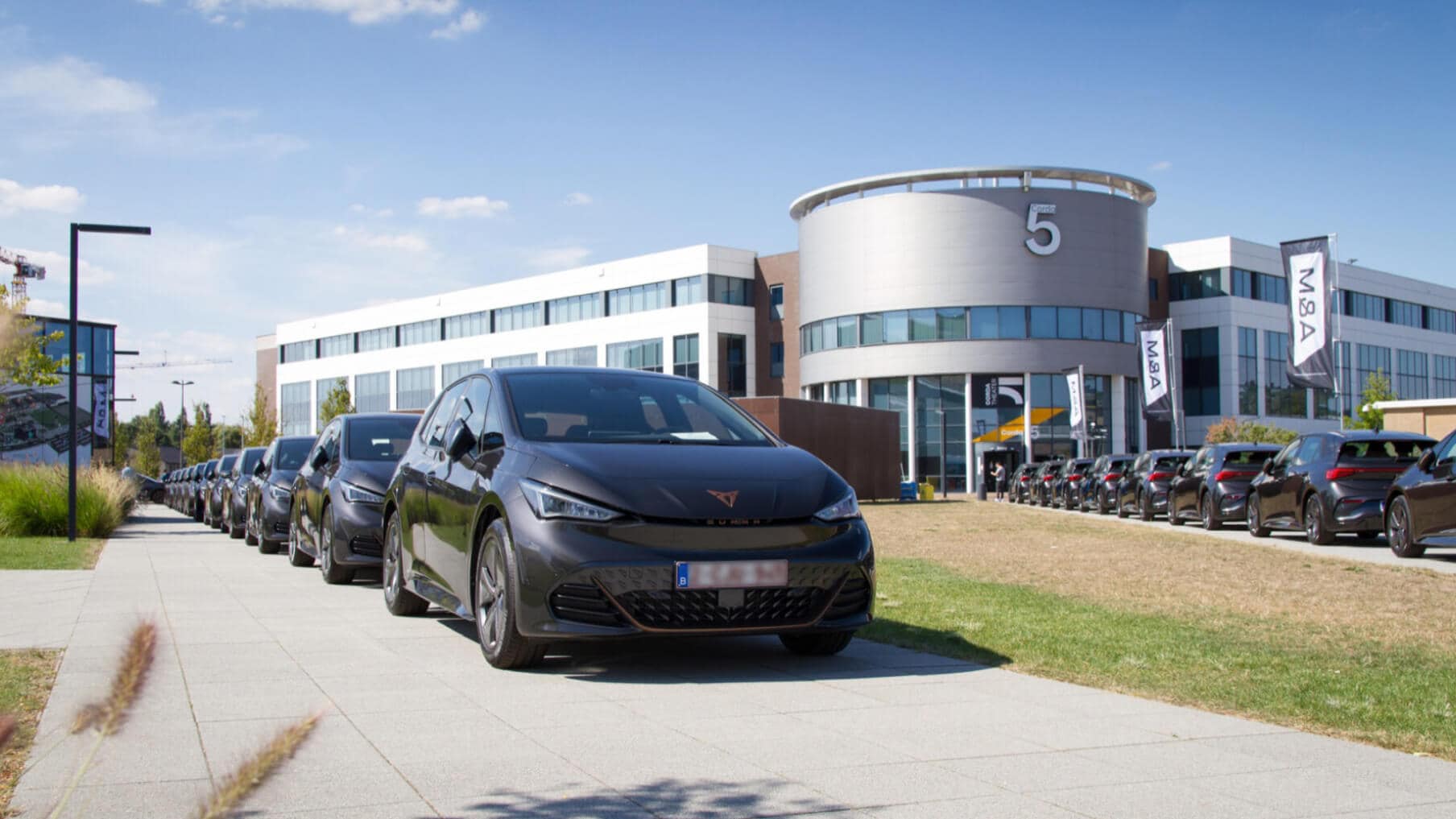 Solutions de gestion de flotte de véhicules d’entreprise CUPRA à l’extérieur d’un immeuble de bureaux moderne.