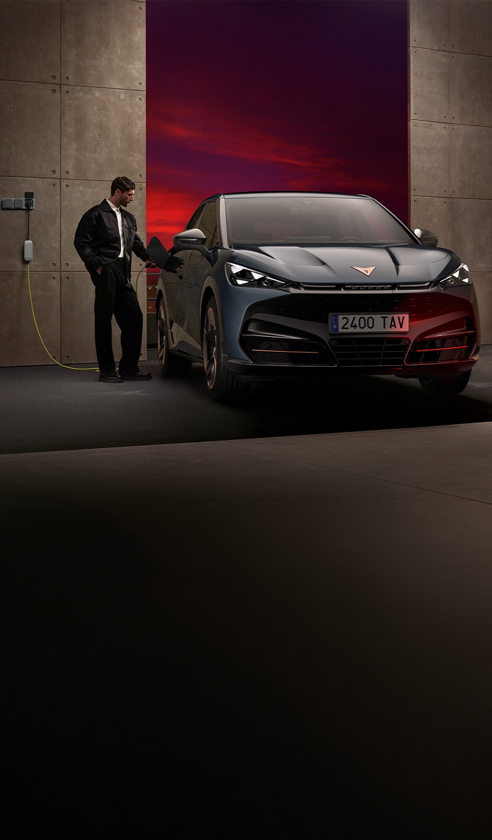 Une personne raccorde un CUPRA Tavascan à une borne dans un garage moderne.