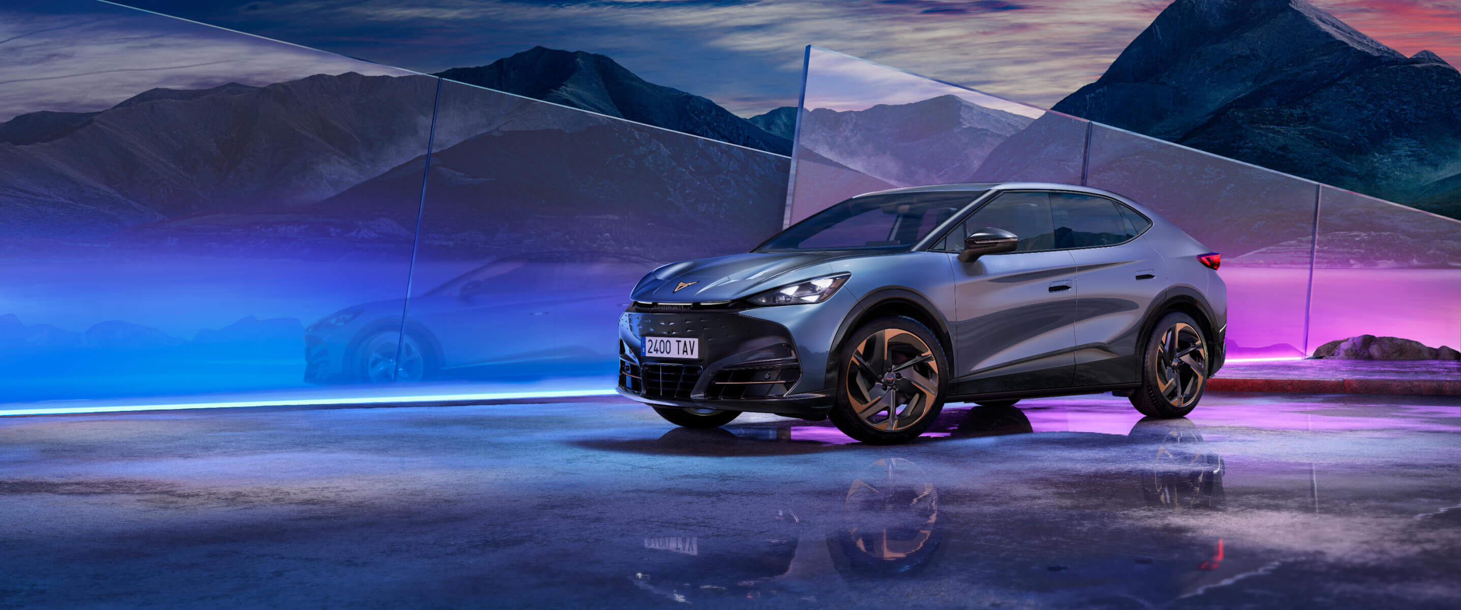 Une CUPRA Tavascan grise, vue de face, entourée de lumières tamisées aux couleurs multiples.