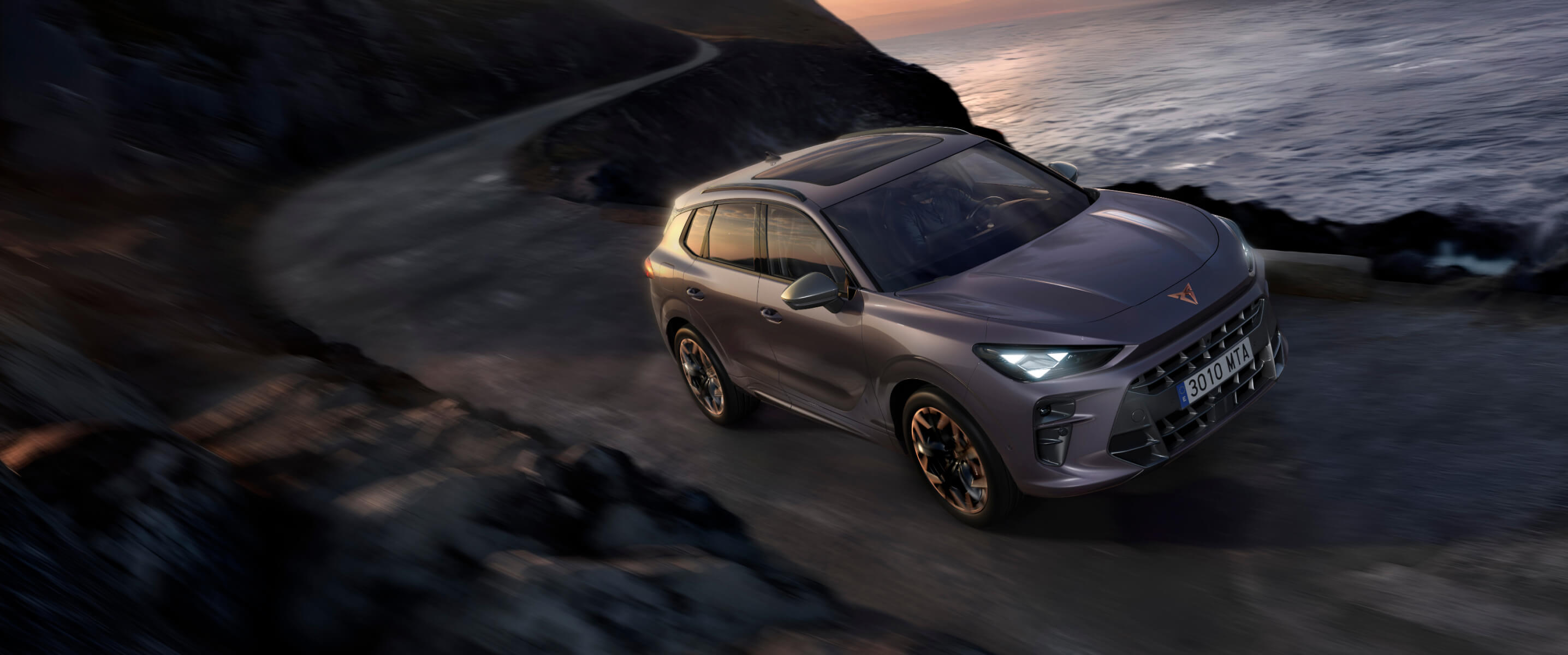 Illustration du freinage régénératif par la CUPRA Terramar VZ hybride rechargeable roulant sur la côte au coucher du soleil, vue de face.