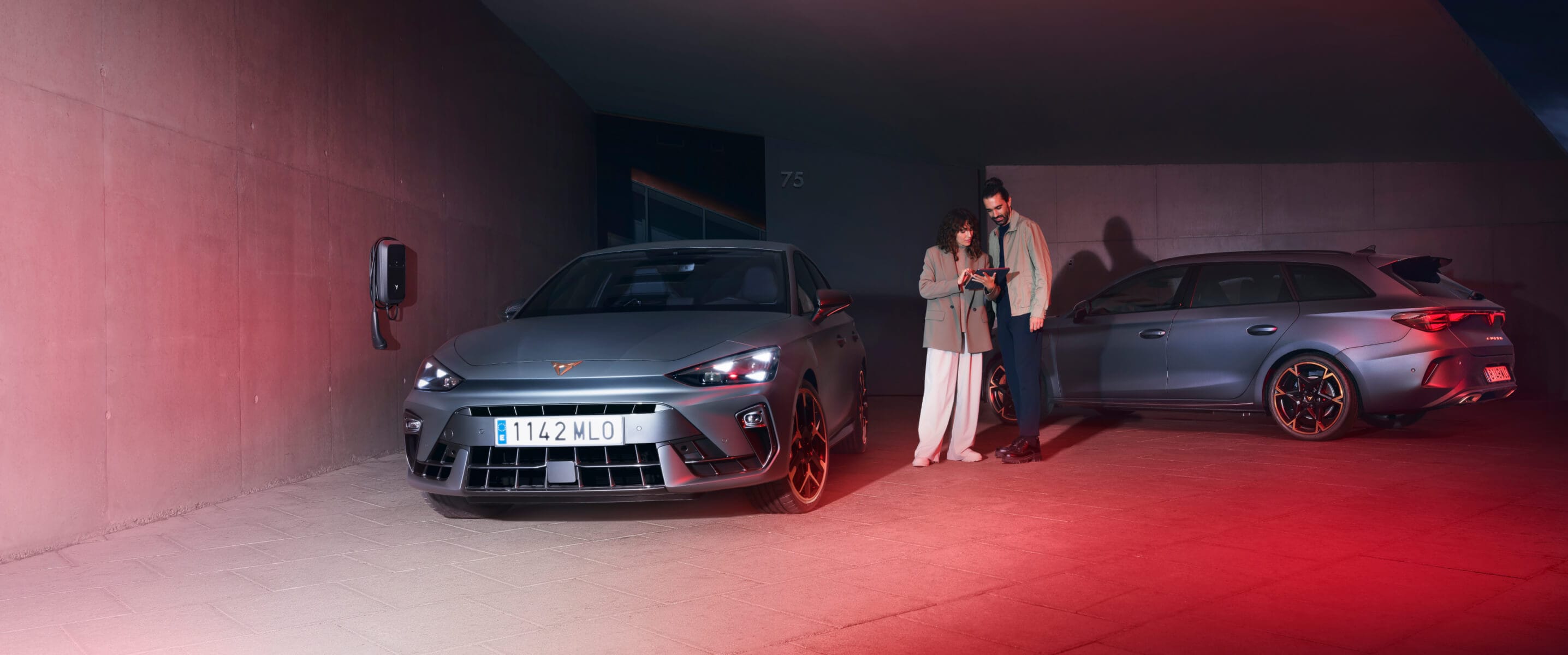 Une CUPRA bleu vif en train de charger dans un parking intérieur, avec une femme vêtue de blanc à ses côtés.