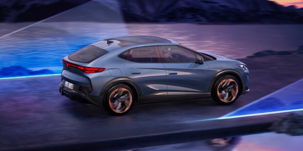 La CUPRA Tavascan électrique roulant le long d’une route côtière pittoresque au coucher du soleil, avec un paysage montagneux et des faisceaux lumineux futuristes, mettant en valeur un design innovant.