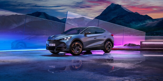 Une CUPRA Tavascan grise, vue de face, entourée de lumières tamisées aux couleurs multiples.