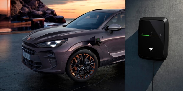 Une voiture électrique CUPRA en gris foncé en train de se recharger et le chargeur dédié.