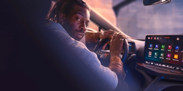 Un homme au volant d’une voiture électrique qui regarde sur le côté.