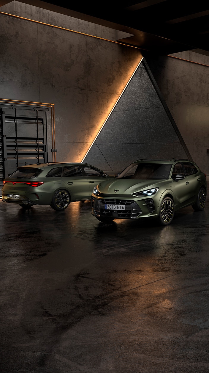 Un gros plan à hauteur des yeux montre la Cupra Formentor VZ5 et la Cupra Leon Sportstourer VZ5, garées dans un garage industriel moderne.